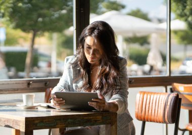 Bir kafede çalışırken dijital tablet kullanan bir iş kadını. Teknoloji konsepti.