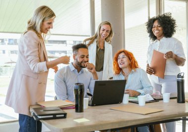Ofiste çalışırken gülümseyen ve eğlenen çok ırklı iş arkadaşları. İş konsepti.