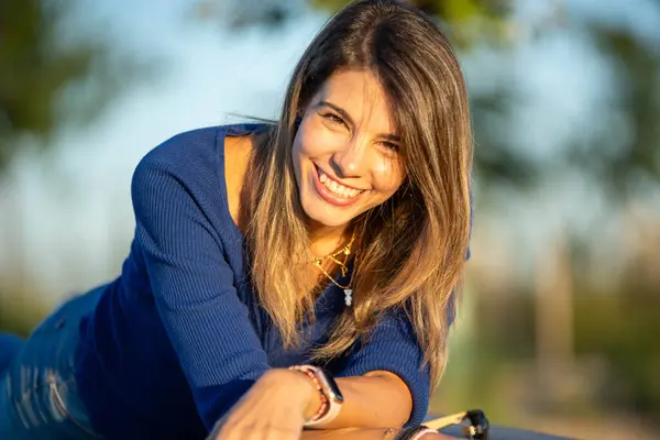 Mutlu kadın gün batımında dışarıda eğlenirken kameraya bakıyor ve gülümsüyor..