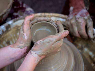 Potter torna üzerinde bir kil pot oluşturmak için elleri ile bir kız yardımcı olur