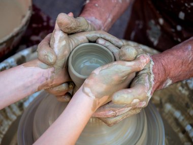 Potter torna üzerinde bir kil pot oluşturmak için elleri ile bir kız yardımcı olur