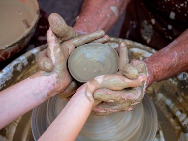 Potter torna üzerinde bir kil pot oluşturmak için elleri ile bir kız yardımcı olur