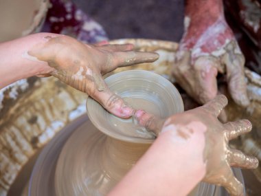 Potter torna üzerinde bir kil pot oluşturmak için elleri ile bir kız yardımcı olur