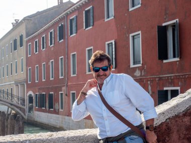 Venedik, İtalya 'da bir köprüde poz veren güneş gözlüklü bir turist. Turizm konsepti.