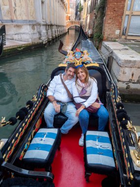 İtalya, Venedik 'te gondolun keyfini çıkarırken gülümseyen bir çift. Turizm ve ulaşım kavramı.