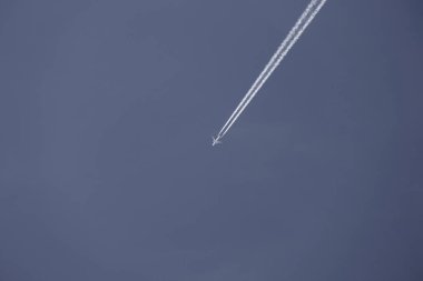 Beyaz, bulutsuz bir gökyüzünde, bir uçağın arkasında zıtlaşıyor.