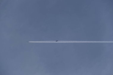 Beyaz, bulutsuz bir gökyüzünde, bir uçağın arkasında zıtlaşıyor.