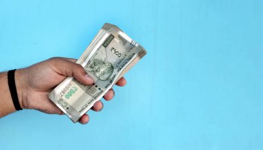 Bir Man Hand 500 rupilik banknot tutuyor.