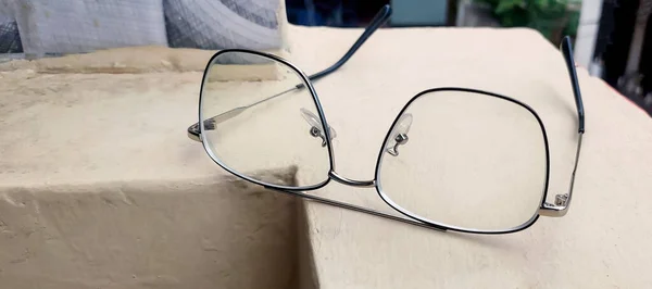 Stylish eye glasses in metal frame on balcony wall. Glasses that correct eyesight from blurred to sharp