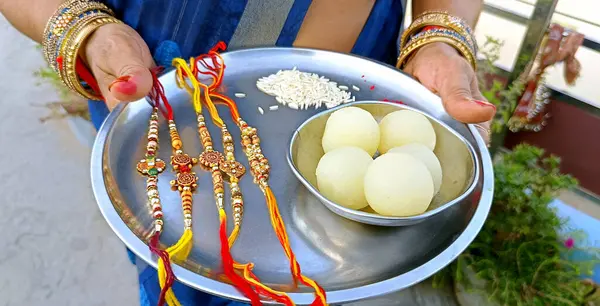 Raksha Bandhan vesilesiyle elinde bir tabak rakhi ve tatlı tutan Hintli bir rahibe.