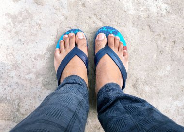 Beton zeminde terlik giyen Hintli bir adamın ayakları