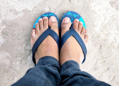 Beton zeminde terlik giyen Hintli bir adamın ayakları