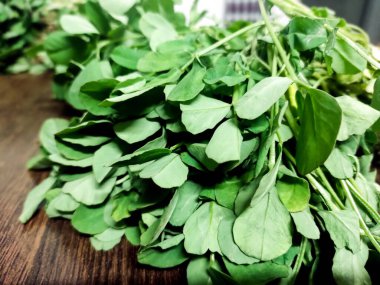 Tahta bir yüzeye yerleştirilmiş taze yeşil çemen yaprağı (metit). Aşçılık, organik gıda ve bitkisel sağlıkla ilgili konular için ideal.