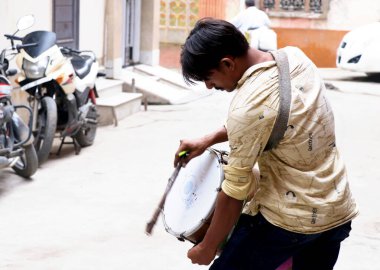 Delhi, Hindistan, 21 Haziran 2024: Bir sokak kutlaması sırasında geleneksel davul çalan bir adam, kültürel şenliklerin ritmini ve enerjisini sergiliyor.