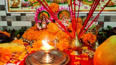 Tanrıça Lakshmi ve Lord Ganesha 'nın heykellerini süsleyen süslü puja süslemeleri. Canlı kadife çiçekleri, tütsü çubukları, yağ lambaları, meyveler ve geleneksel Hindu festivali kutlamalarında sunulan hediyeler..