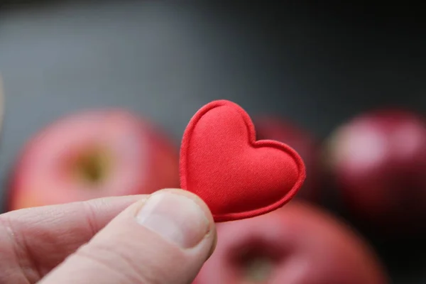 Healthy food idea. Hand holding a heart on the background of an apple.