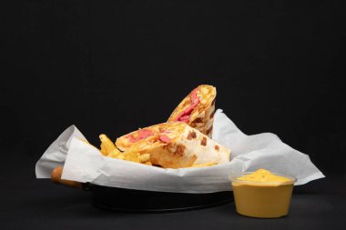 Fransız Patates ve Peynir Sosu ile Savory Burrito Paketi: Meksika 'dan esinlenilmiş Fast Food Meal on White Paper, Black Pground, Wooden Handle Knife.