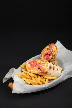 Fransız Patates ve Peynir Sosu ile Savory Burrito Paketi: Meksika 'dan esinlenilmiş Fast Food Meal on White Paper, Black Pground, Wooden Handle Knife.