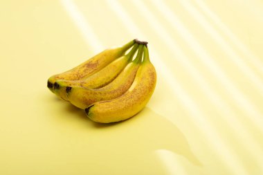 Close-up of a bunch of ripe yellow bananas with slight brown spots, indicating peak ripeness. Isolated on a pale yellow background, perfect for showcasing this popular tropical fruit as a healthy snack or versatile cooking ingredient. clipart