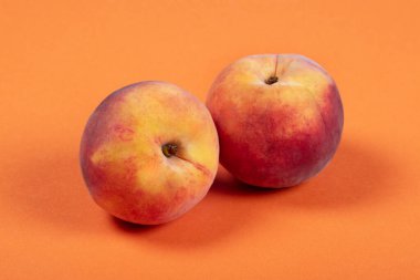 Two Fresh Peaches on Vibrant Orange Background  Minimalist Fruit Photography for Healthy Eating, Summer, and Organic Produce Concepts clipart