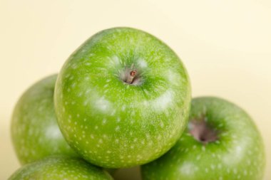 Taze Yeşil Elmalar: Soluk Sarı Arkaplandaki Gevrek Granny Smith Fruits Üçlüsü - Sağlıklı Atıştırma, Organik Üretim ve Minimalist Ayarlarda Doğal Yaşamlılık