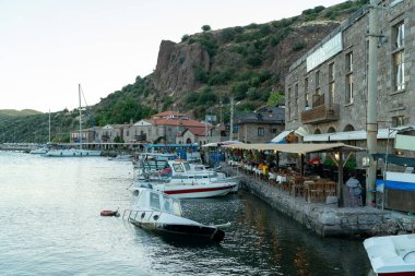 Güneşli bir günde Assos Limanı 'nın Taş Evleri, Tekneleri ve Ege Denizi manzarası