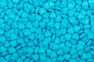 Pürüzsüz bir zemin oluşturan parlak yüzeyi olan mavi kalp şeklinde şekerler. Sevgililer Günü, aşk ve romantizm temaları için mükemmel bir şekerleme dokusu..