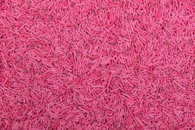 Pişmemiş, pembe vermicelli makarnanın yakın çekimi, desenli arka planda dağınık küçük silindirik erişteler. Yemek, ambalaj ve malzeme kavramları için ayrıntılı gıda dokusu ideal.