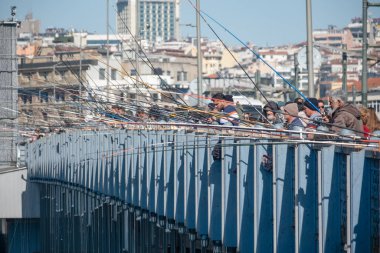 03.06.2025, İstanbul, Türkiye. İstanbul 'daki Galata Köprüsü' nde Balıkçılar: Şehir Arkaplanı Kalabalık Şehir Balıkçılık Mekanı, Mavi Raylı Yapı ve Balıkçılar Kentin Gökyüzüne Karşı Olta Oltaladılar