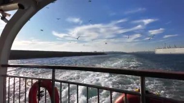 Güneşli bir günde İstanbul Boğazı 'nda Feribot Takip Eden Martılar, Wake Trails, City Skyline View ve Harbor Breakwater - Deniz Yolculuğu Deniz Güvertesi Perspektifi