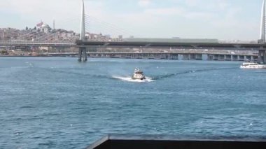 İstanbul 'daki Galata Köprüsü' nden feribotlar, yolcu botları ve Martıların Güneşli Bir Deniz ve Şehir Sahnesinde Boğaz Üzerinde Uçuşu Manzarası