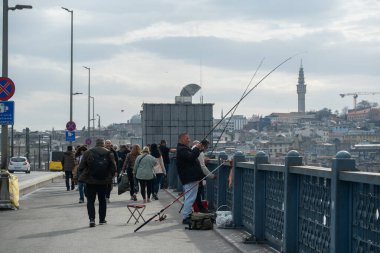 03.13.2025, İstanbul, Türkiye, köprüde manzaralı bir şehir manzarası olan yaşlı adam, kubbeler ve sakin bir gökyüzü ile sakin bir eğlence ve gelenek anı yakalıyor.