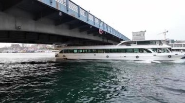 03.13.2025, Galata Köprüsü Seyahati: İstanbul 'da Tarihsel Köprü Altından Geçen Tur Teknelerinde Boğazın Tadını Çıkaran Turistler