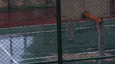 Rusty Basketball Hoop in the Rain with Swaying Net and Raindrops Falling on Wet Court - Terk Edilmiş Açık Hava Spor Alanında Rüzgarlı Bir Gün