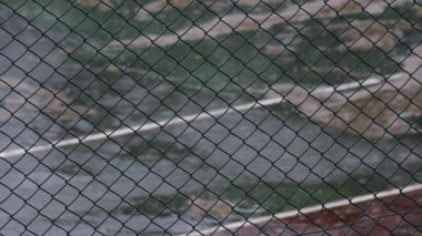 Rusty Basketball Hoop in the Rain with Swaying Net and Raindrops Falling on Wet Court - Terk Edilmiş Açık Hava Spor Alanında Rüzgarlı Bir Gün