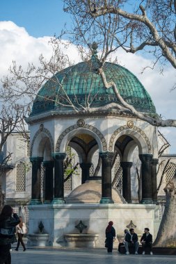 04.03.2025, İstanbul. İstanbul Sultanahmet Meydanı 'nda Süslü Yeşil Kubbe ve Bizans Tarzı Mimariyle Tarihi Alman Çeşmesi - Türk Tarihi Simgelerini Keşfeden Ziyaretçilerle Osmanlı Dönemi Anıtı