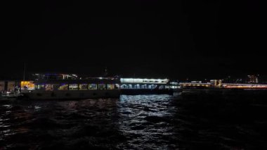 04.03.2025, İstanbul, Türkiye. Yolcu gemileri geceleyin Eminn rıhtımında yolcuları bindirip indiriyor. Arka planda Galata Köprüsü 'nün ışıkları görünür..