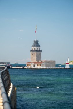 05.14.2025, İstanbul, Türkiye. İstanbul 'daki tarihi Bakire Kulesi' nde güneşli bir günde rıhtıma yanaşan gezici tekneler, Boğaziçi suları, mavi gökyüzü, şehir silüeti ve ikonik Türk mimarisi yer alıyor.