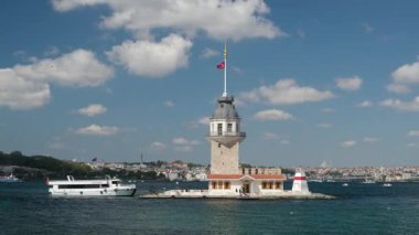 05.14.2025, İstanbul, Türkiye. İstanbul 'daki tarihi Bakire Kulesi' nde güneşli bir günde rıhtıma yanaşan gezici tekneler, Boğaziçi suları, mavi gökyüzü, şehir silüeti ve ikonik Türk mimarisi yer alıyor.