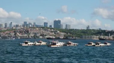 05.14.2025, İstanbul, Türkiye. İstanbul, Türkiye 'deki Boğaz Köprüsü' nün altından geçen büyük gemilerle İstanbul 'da balıkçı tekneleri manzaralı bulutlar ve arka planda tepelerle aydınlık bir günde.