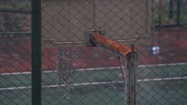 Terk Edilmiş Basketbol Sahası Rusty Hoop ve Sarkık Ağ Zincirleme Bağlantı Çitlerinin Arkasında - Yağmurlu Gün 'de Boş Açık Hava Spor Alanı ve Kasvetli Atmosfer