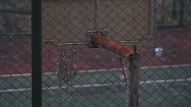 Terk Edilmiş Basketbol Sahası Rusty Hoop ve Sarkık Ağ Zincirleme Bağlantı Çitlerinin Arkasında - Yağmurlu Gün 'de Boş Açık Hava Spor Alanı ve Kasvetli Atmosfer