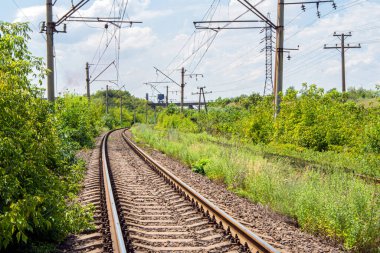 Demiryolu manzarası var. Mavi gökyüzünün arka planında bulutlu demiryolu.