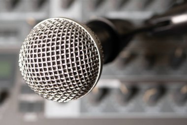 Bir müzik sentezleyicisinin arka planına karşı dinamik mikrofon. Arka plan bulanık. Yakın plan..