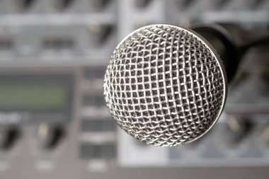 Bir müzik sentezleyicisinin arka planına karşı dinamik mikrofon. Arka plan bulanık. Yakın plan..