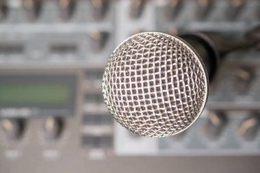 Bir müzik sentezleyicisinin arka planına karşı dinamik mikrofon. Arka plan bulanık. Yakın plan..