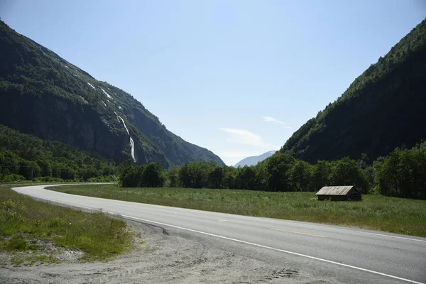 Dağlarda yol, Norveç. Yol, dağ ve küçük evle yaz manzarası.