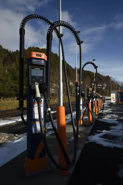 Bir dizi yüksek güçlü 150 kW 'lık elektrikli araç (EV), arka planda ağaçlar ve mavi gökyüzü bulunan karlı bir açık hava ortamında şarj istasyonları. Aalesund, Norveç - 17 Şubat 2024