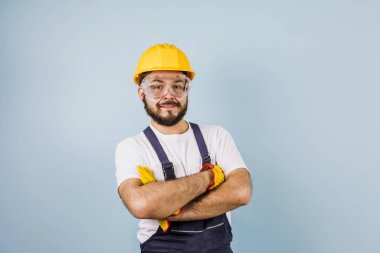 portrait of Hispanic bearded young man engineering and worker with hard helmet in Mexico Latin America on blue background