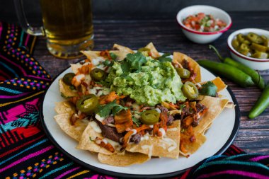Mexican Nachos with cheese or tortilla chips with meat, avocado and beer, tex mex food in Mexico America